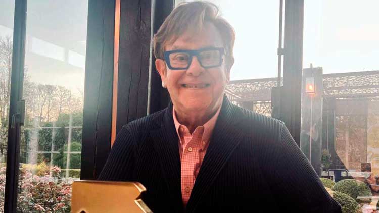Elton John con el trofeo por su nuevo número 1 en álbumes en Reino Unido